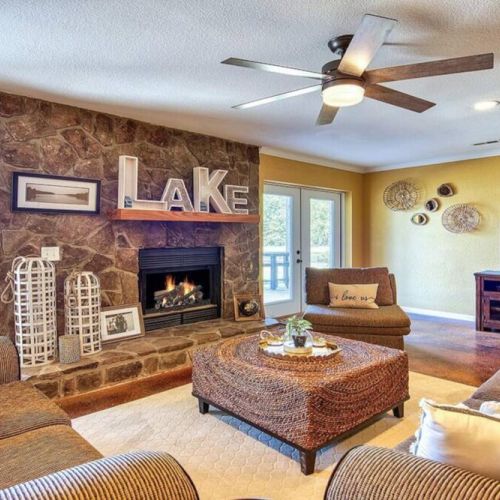 Lower level living room area with lots of overstuffed seating near another gorgeous fireplace and view of the lake.
