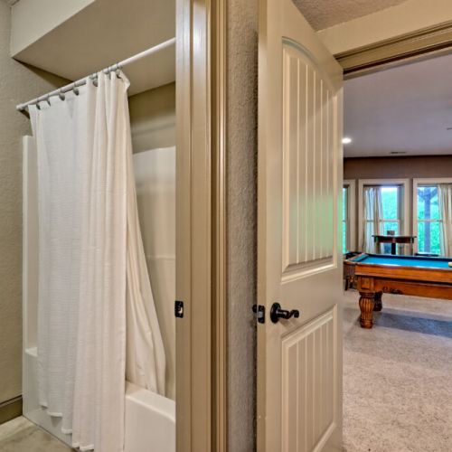 Basement level bathroom looking out to pool table.